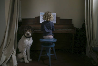 Boy sitting by girl playing piano at home
