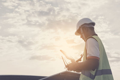 Side view of man standing against sky at sunset