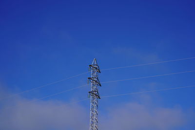 Low angle view of electricity pylon against blue sky