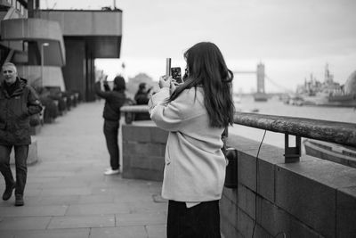 Rear view of a woman photographing with city in background