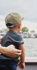 Close-up of cute boy standing in river against sky