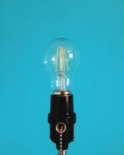 Close-up of light bulb against blue wall