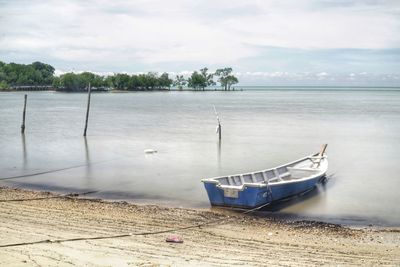 Boat moored on beach against sky