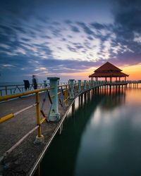 Pier over sea against sky at sunset