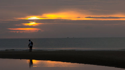 Silhouette man on beach against sky during sunset