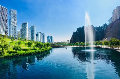 View of fountain by lake against buildings in city