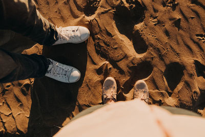 Low section of people standing on sand at beach