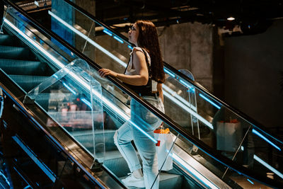 Young brunette latina attractive woman with shopping bags on escalator in the fashion store mall.