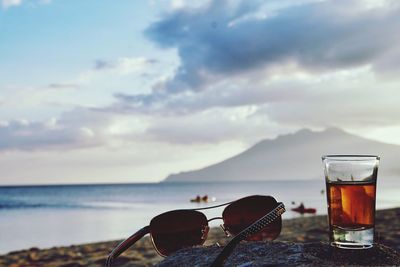 Beer glass on beach against sky