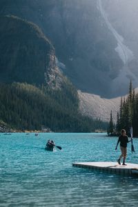 People on lake against mountains