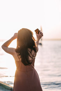 Rear view of woman standing in sea against sky