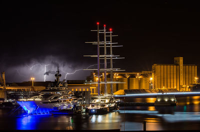 Sailboats moored at harbor against sky at night