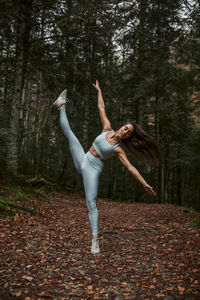 Woman with arms raised standing in forest