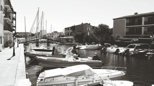 Boats moored on harbor in city by sea