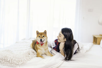 Young woman with dog lying on bed at home
