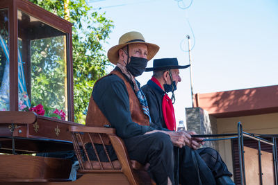 Senior adult men riding antique cart in south american festival