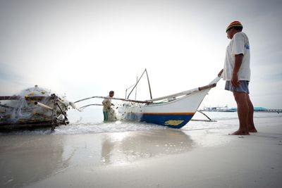 Men fishing in sea against sky