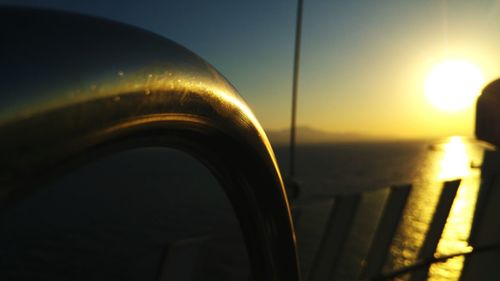 Close-up of sea seen through railing during sunset