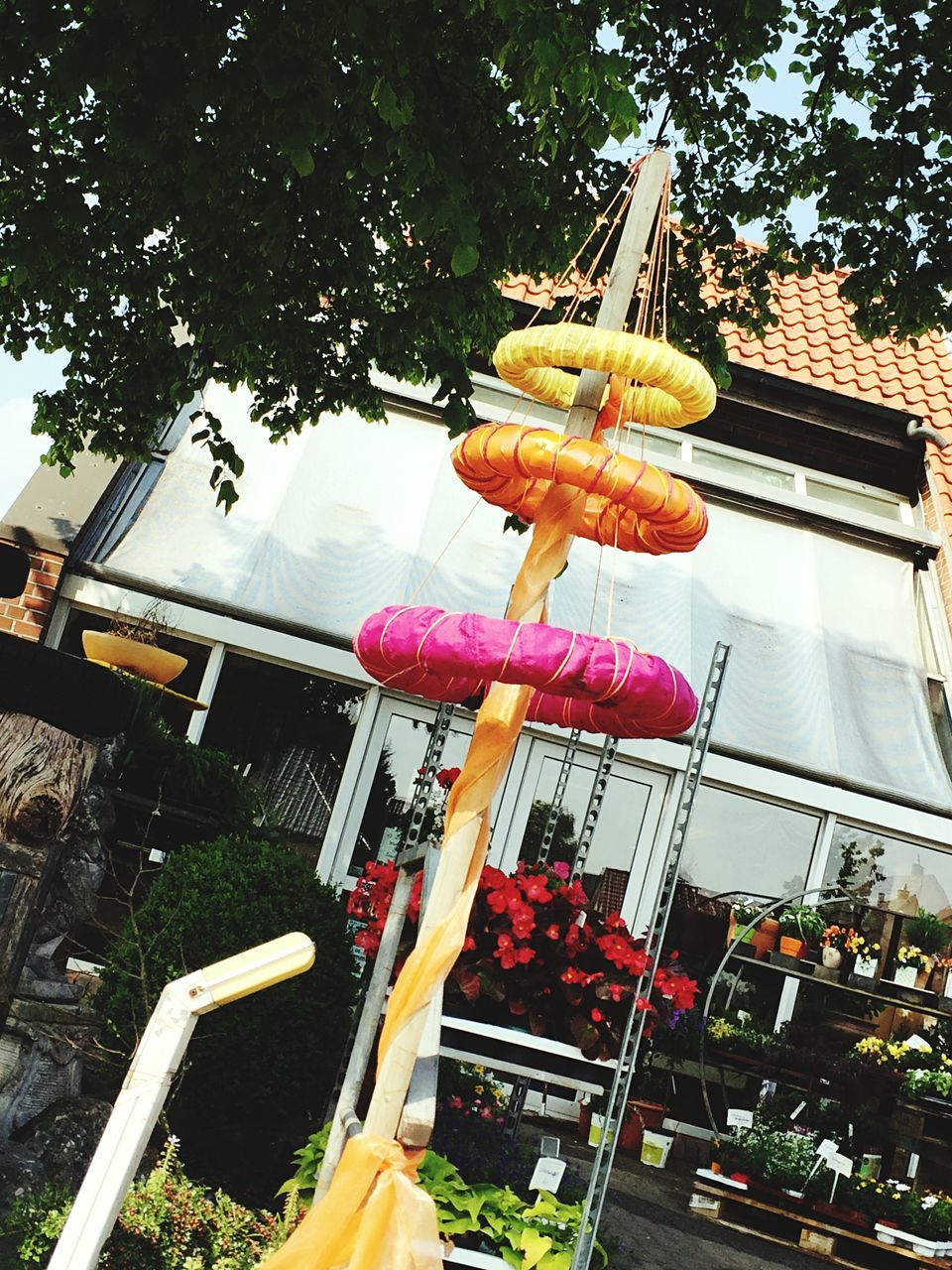 food and drink, low angle view, tree, outdoors, metal, day, food, built structure, architecture, part of, freshness, hanging, building exterior, close-up, cropped, sunlight, tradition, no people, high angle view, tilt