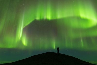 Silhouette person standing on field against sky at night