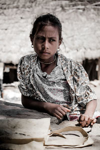 Girl looking away while sitting on rock