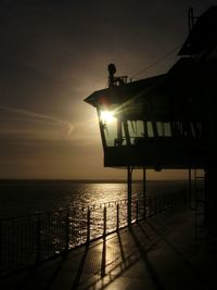 Silhouette built structure by sea against sky during sunset