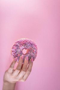 Close-up of hand holding ice cream against pink background