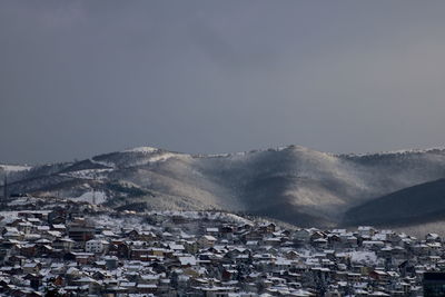 Aerial view of townscape and mountains against sky