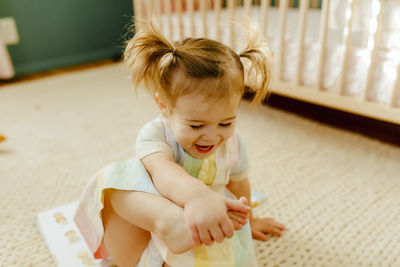 Cute baby girl sitting on floor at home