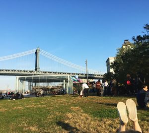 People on suspension bridge against clear blue sky