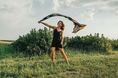 Beautiful woman with dark long hair waving a scarf. light fabric flutters in the wind.