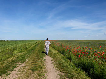 Rear view of person on field against sky