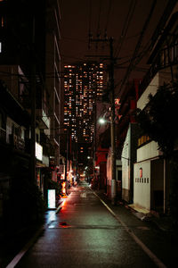 Illuminated street amidst buildings in city at night