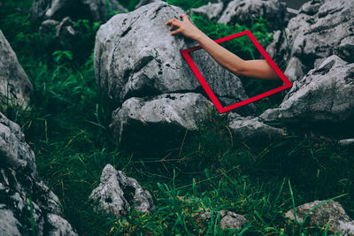 Cropped hand on woman on rock