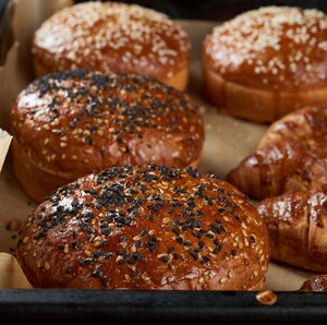 Baked sesame buns on brown parchment paper, ingredient for a hamburger, close up