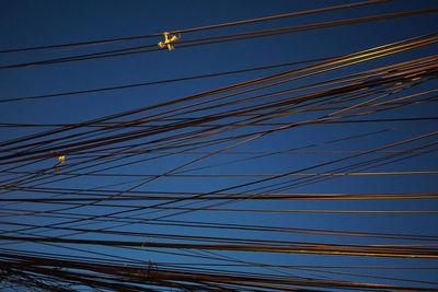 Low angle view of power lines against blue sky