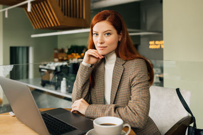 Young woman using mobile phone while sitting on table