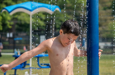 Young boy basks in the cool water at a summertime splash pad