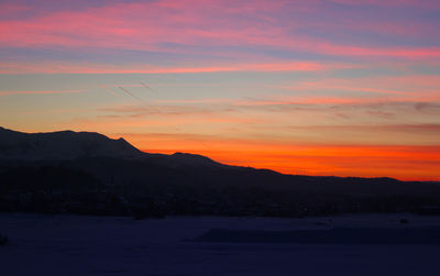 Scenic view of silhouette mountains against romantic sky at sunset