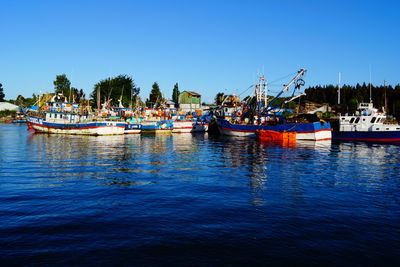 Boats in calm sea against clear sky