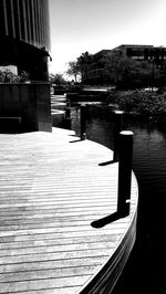 Pier over river by buildings against clear sky