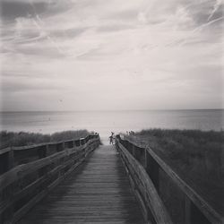 Pier on sea against cloudy sky