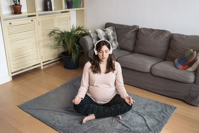 Young woman sitting on sofa at home