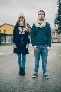 Full length of sad couple looking away while standing on road