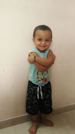 Portrait of smiling girl standing against wall