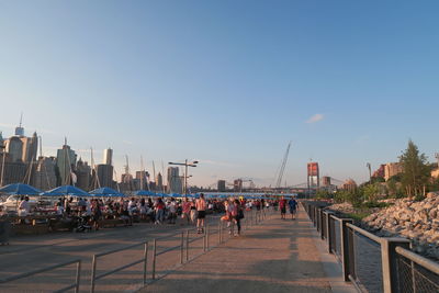 People on city street against clear blue sky
