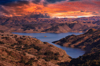 Scenic view of lake by mountains against sky during sunset