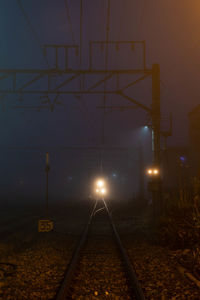 Illuminated railroad tracks against sky at night