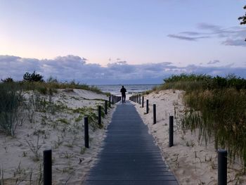 Rear view of pier on sea against sky