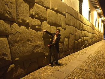 Woman using phone while standing on street at night